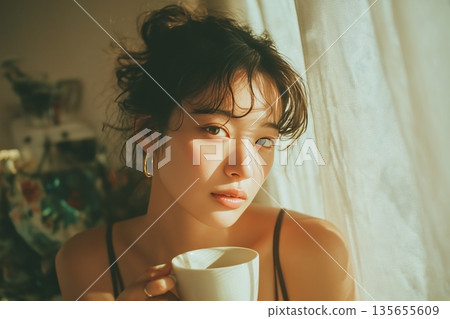 一位年輕的日本女性在晨光中悠閒地喝咖啡。 135655609