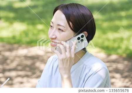 Woman making a phone call on a smartphone outdoors Woman making a phone call on a smartphone outdoors 135655676