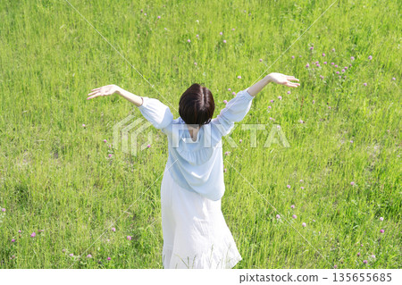 Woman taking a deep breath in the field, overhead view, back view 135655685