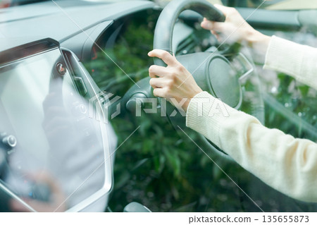 Hand of a woman driving a car Hand of a woman driving a car 135655873