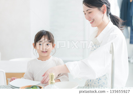 Parents and children cooking and washing dishes in the kitchen, helping mom like they're playing house 135655927