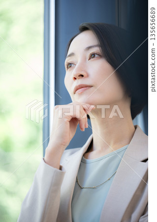 一位女商人倚窗沉思,擔憂自己的事業,她該如何考慮換工作? 一位女商人倚窗沉思,擔憂自己的事業,她該如何考慮換工作? 135656689