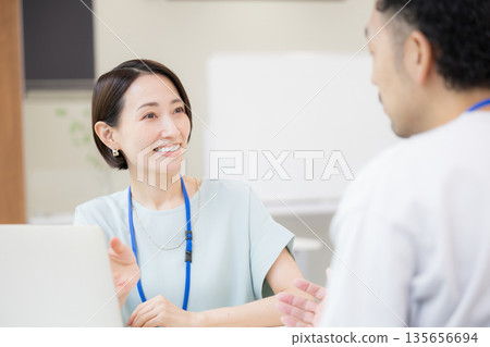 一張令人耳目一新的照片：一位佩戴名牌的女銷售員正在向顧客和同事講解產品訊息並進行會面。講解和演示。春夏系列 135656694