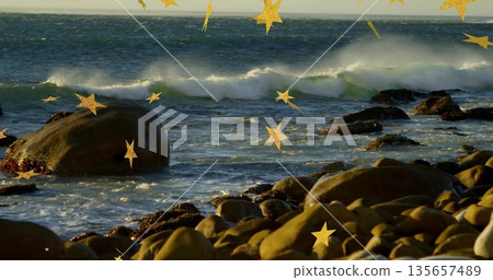 Ocean waves rolling and breaking on rocky shoreline, with round boulders and golden star sparkles 135657489