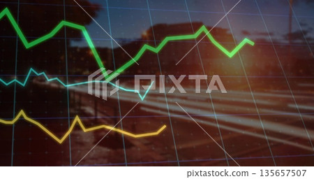 Displaying tri color line graph curves over gridlines, blurred rural railway at dusk with sun flare 135657507