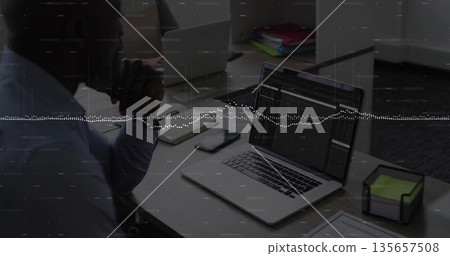 Analyzing man in business shirt studying laptop at office desk, with neon sticky notes, copy space 135657508
