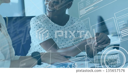 Colleagues in blouses analyzing printed documents and charts in meeting room, with coffee and phone 135657576