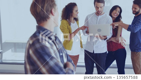 Collaborating team of five professionals sharing ideas in modern meeting area, with laptop computer 135657588