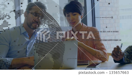 Team reviewing laptop at wooden table in office, with phones, notepad, pen, dotted map partition Team reviewing laptop at wooden table in office, with phones, notepad, pen, dotted map partition 135657663