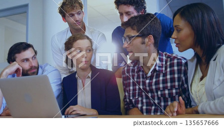 Collaborating business casual professionals typing and discussing around laptop on table in office 135657666