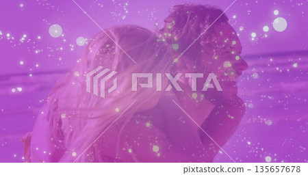 Carrying man in swim trunks holding woman in swim top along shoreline with sand, waves, horizon Carrying man in swim trunks holding woman in swim top along shoreline with sand, waves, horizon 135657678