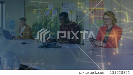 Three business professionals collaborating in glass meeting room, digital devices and sticky notes 135658865