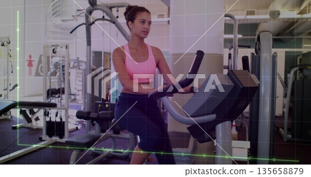 Pedaling woman wearing pink bra and leggings gripping handlebars on bike in gym, with dumbbells Pedaling woman wearing pink bra and leggings gripping handlebars on bike in gym, with dumbbells 135658879