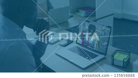 Consultant listening to shop owner via laptop in office, smartphone notebook sticky note cube Consultant listening to shop owner via laptop in office, smartphone notebook sticky note cube 135658888