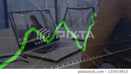 Two laptops showing call interface and hand typing in home office, with blue pen, chart overlay Two laptops showing call interface and hand typing in home office, with blue pen, chart overlay 135658913