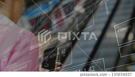 Pink-shirted woman viewing smartphone and analyzing data panels in escalator lobby, copy space Pink-shirted woman viewing smartphone and analyzing data panels in escalator lobby, copy space 135658937