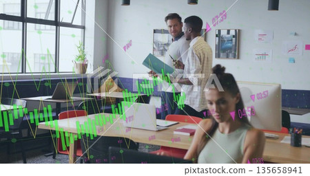 Standing two men in casual dress discussing project at open office, with tablet and graph overlays 135658941