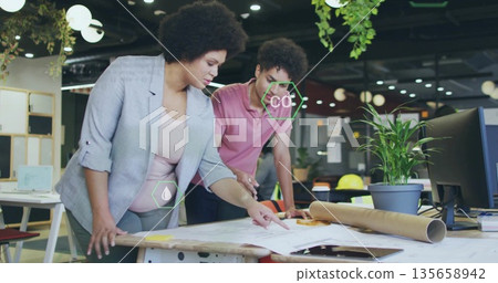 Reviewing blueprint sheets, professionals in business attire collaborating at office with notes 135658942