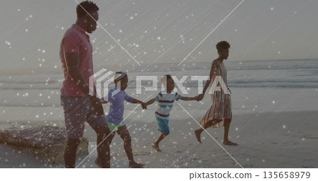 Walking family of four holding hands along wet shoreline at sandy beach, pastel sky Walking family of four holding hands along wet shoreline at sandy beach, pastel sky 135658979