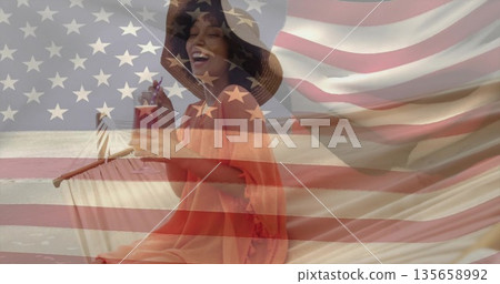 Smiling woman wearing coverup sitting on chair holding cocktail with flag on shore, flag overlay 135658992