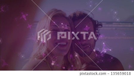 Posing man and woman smiling at recorder on beach with waves, animated constellations drifting Posing man and woman smiling at recorder on beach with waves, animated constellations drifting 135659018