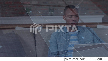 Sitting man focusing on holographic grid panels above sofa in living room, brick mantel, copy space 135659038