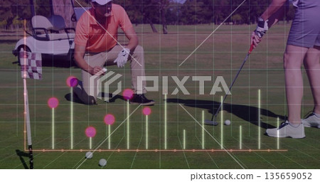 Standing woman lining up putt on sunlit green with crouching partner checking line via AR overlay Standing woman lining up putt on sunlit green with crouching partner checking line via AR overlay 135659052