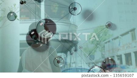Walking woman wearing white tank top along city sidewalk, with tote bag and digital network overlay 135659107