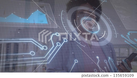 Holding smartphone, woman wearing blazer and glasses reviewing holographic interface data in office Holding smartphone, woman wearing blazer and glasses reviewing holographic interface data in office 135659109