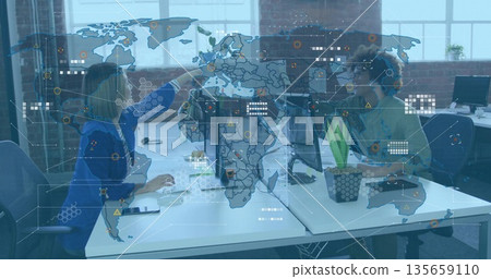 Woman in blue blazer and coworker leaning and pointing at monitors in loft office, with smartphone Woman in blue blazer and coworker leaning and pointing at monitors in loft office, with smartphone 135659110