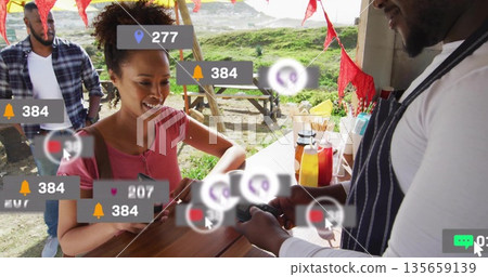 Handing card woman wearing red T-shirt paying at outdoor stall, with overlay icons, copy space Handing card woman wearing red T-shirt paying at outdoor stall, with overlay icons, copy space 135659139