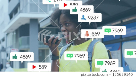 Talking commuter using smartphone at bus stop with earphones backpack and social media overlays Talking commuter using smartphone at bus stop with earphones backpack and social media overlays 135659140