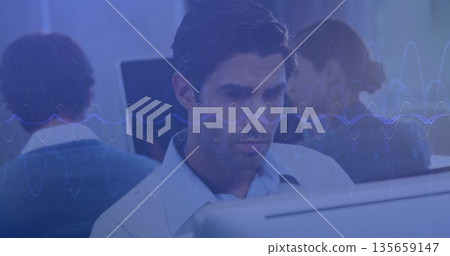 Working mid adult man in blue shirt analyzing audio waveform at monitor in open-plan office 135659147