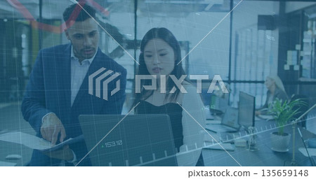 Collaborating colleagues reviewing laptop at open office, with printed report and monitors Collaborating colleagues reviewing laptop at open office, with printed report and monitors 135659148