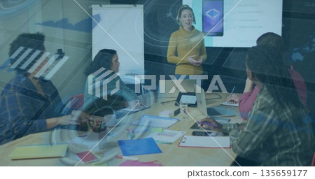 Presenting woman gesturing toward screen at office conference table, with laptops, copy space 135659177