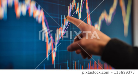 Hand of a person pointing at a financial chart displayed on a large screen, showcasing colorful candlestick patterns and data trends in a modern office environment Hand of a person pointing at a financial chart displayed on a large screen, showcasing colorful candlestick patterns and data trends in a modern office environment 135659373