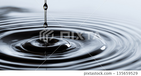Close-up of water droplet creating ripples on a smooth surface, with a soft gradient background enhancing the fluid motion and reflective qualities of the water Close-up of water droplet creating ripples on a smooth surface, with a soft gradient background enhancing the fluid motion and reflective qualities of the water 135659529