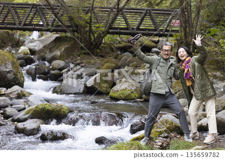 A middle-aged couple strolling along a mountain stream 135659782