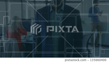 Standing executive in dark suit overseeing open-plan office, with desktop computer and smartphone 135660400