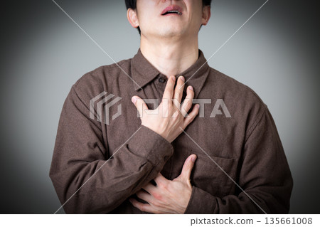 A middle-aged woman suffering while holding her throat 135661008