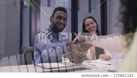 Offering handshake man in blue shirt reaching across meeting table with clipboard, glass partitions Offering handshake man in blue shirt reaching across meeting table with clipboard, glass partitions 135661181