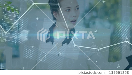 Reacting to data overlays, Asian woman in white blouse speaking at corporate office, with graphs 135661268