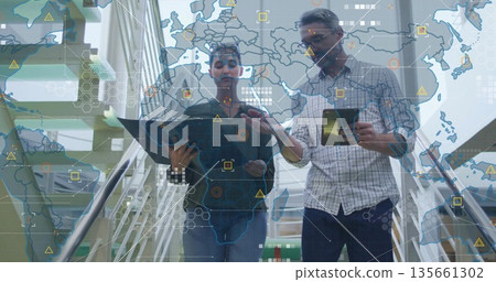 Descending colleagues carrying tablet smartphone laptop on office staircase with world map overlay Descending colleagues carrying tablet smartphone laptop on office staircase with world map overlay 135661302