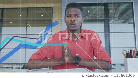 Sitting man wearing red shirt and wristwatch at desk with glass partitions papers chart overlays Sitting man wearing red shirt and wristwatch at desk with glass partitions papers chart overlays 135661309
