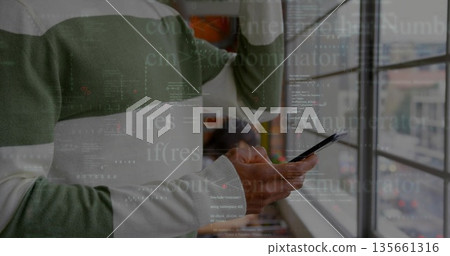 Developer in striped sweater examining smartphone while raising hand in office with code overlay Developer in striped sweater examining smartphone while raising hand in office with code overlay 135661316