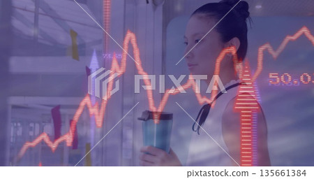 Standing Asian woman holding mug, viewing red charts over sticky notes in office hall, copy space 135661384