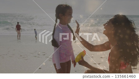 Child girl wearing pink rash guard getting yellow sunscreen applied at sunlit beach, ocean waves Child girl wearing pink rash guard getting yellow sunscreen applied at sunlit beach, ocean waves 135661460