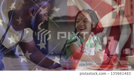 Father and daughter spreading tomato sauce on pizza dough in home kitchen, with flag overlay Father and daughter spreading tomato sauce on pizza dough in home kitchen, with flag overlay 135661483