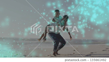 Giving piggyback ride adult man walking on sandy shoreline beach, with child laughing joyfully Giving piggyback ride adult man walking on sandy shoreline beach, with child laughing joyfully 135661492
