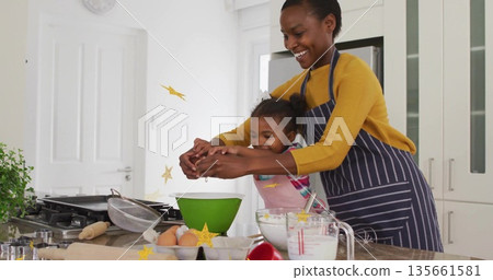 Guiding mother and daughter wearing aprons cracking egg over kitchen island, with green mixing bowl Guiding mother and daughter wearing aprons cracking egg over kitchen island, with green mixing bowl 135661581